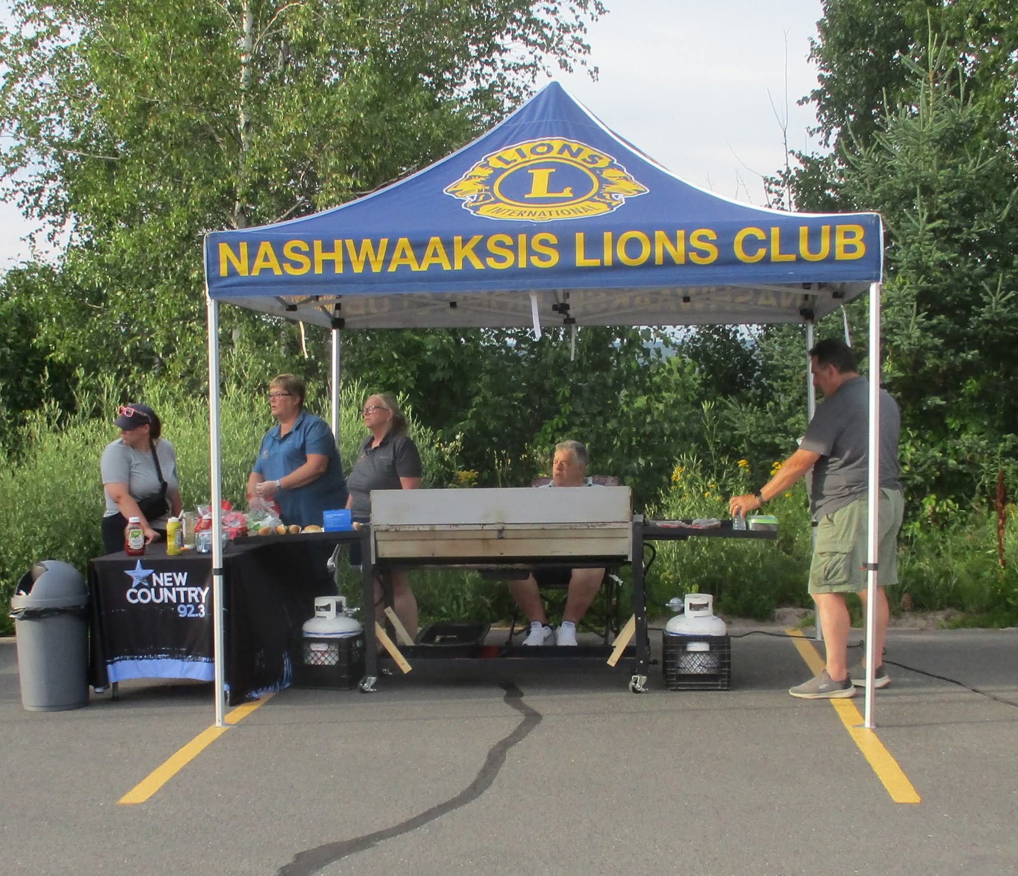 Nashwaaksis Lions Club tent with barbecue and New Country 92.3 table at the Drive-In Bingo night